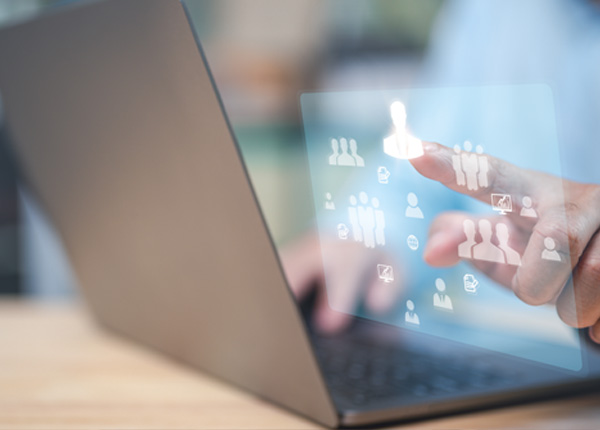 Person using a laptop with a digital interface displaying icons of people and groups, symbolising HR and workforce management.